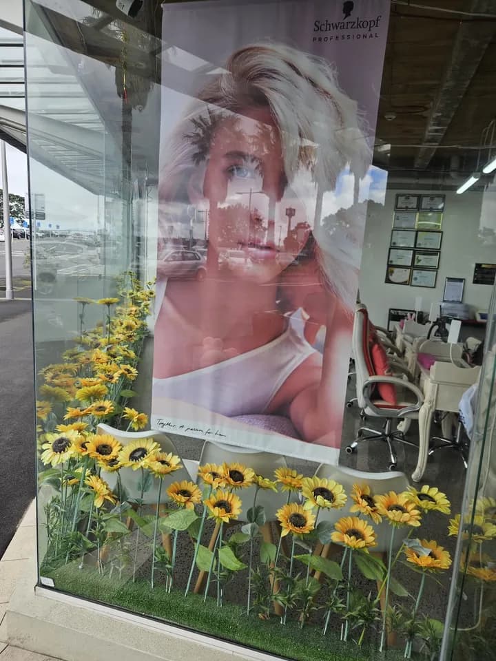 Shopfront window display with a Schwarzkopf Professional poster and sunflowers